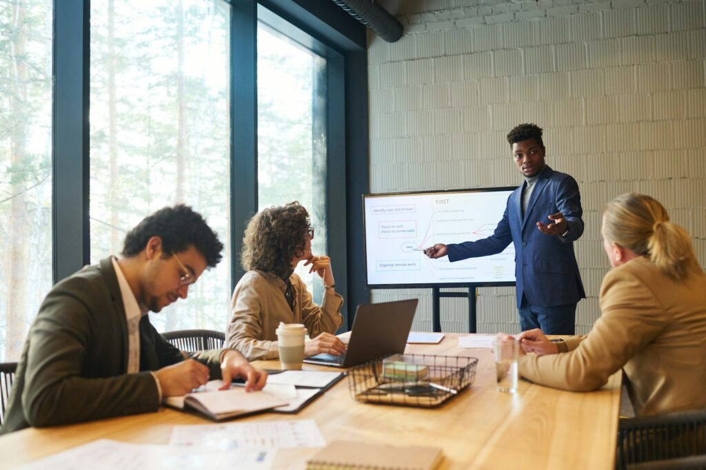 Young confident African American business coach pointing at whiteboard